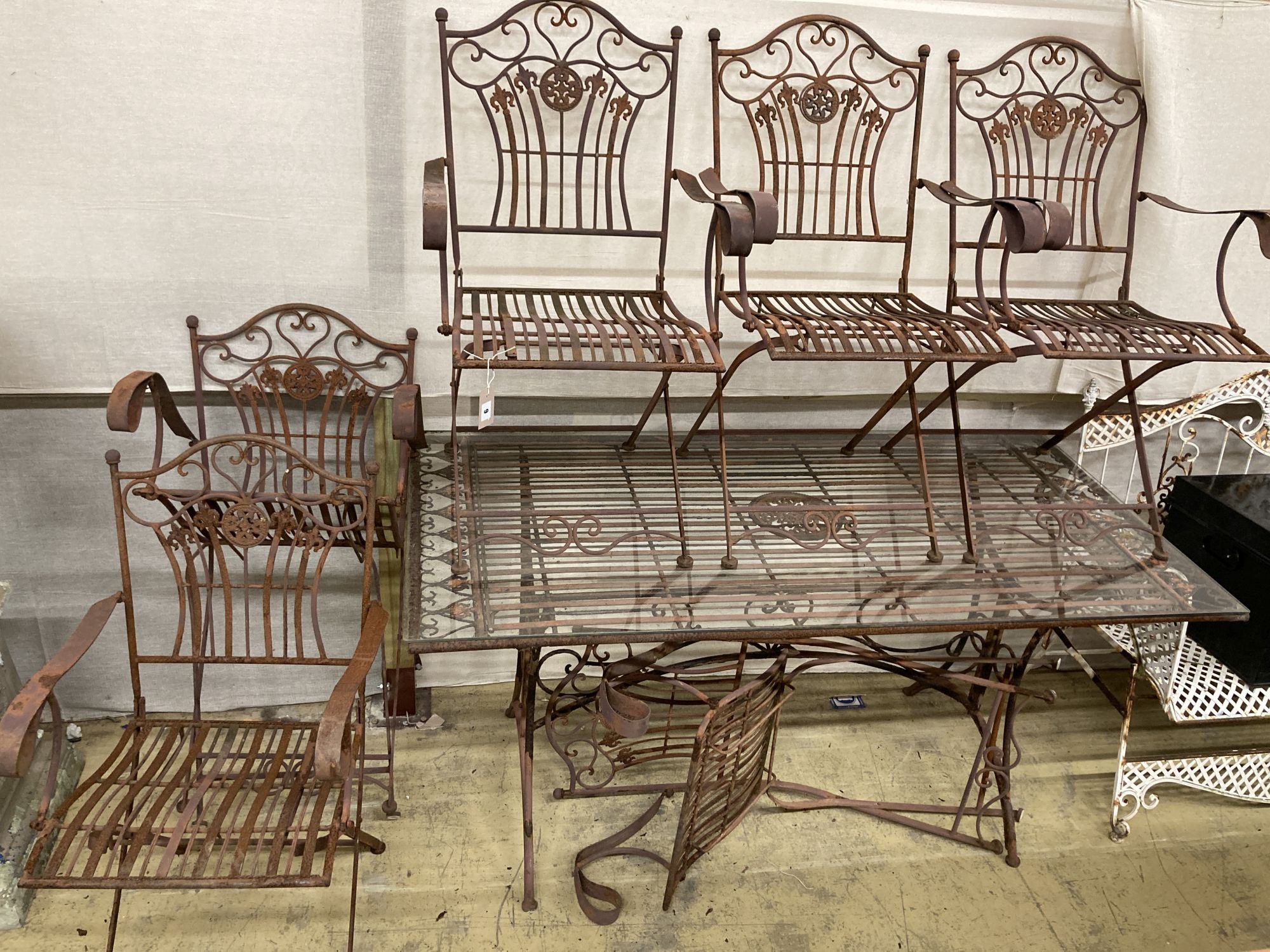 A wrought iron garden table, width 160cm, depth 80cm, height 76cm and six folding chairs
